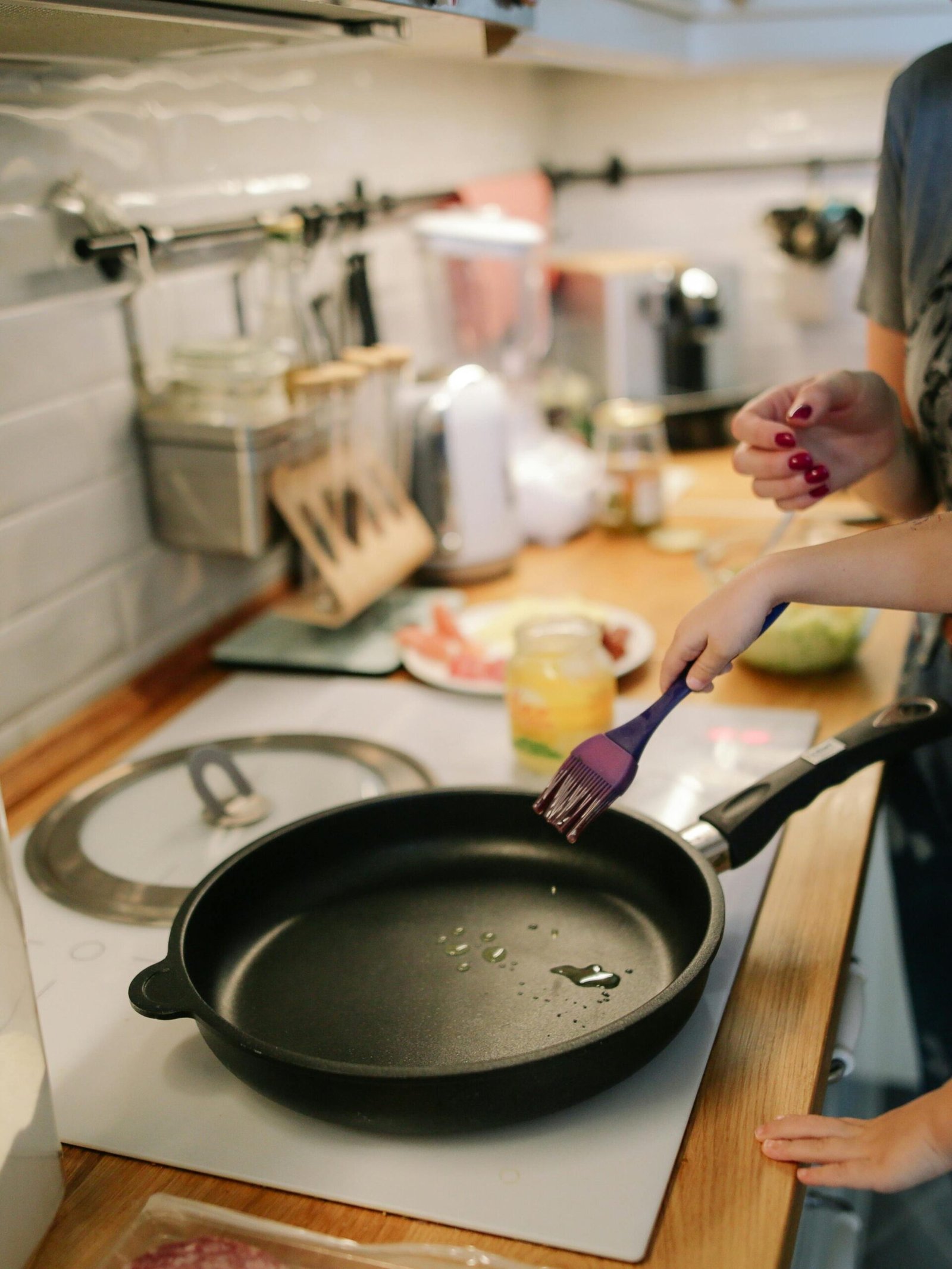 Young girl cooking with a frying pan under adult supervision in a modern kitchen.